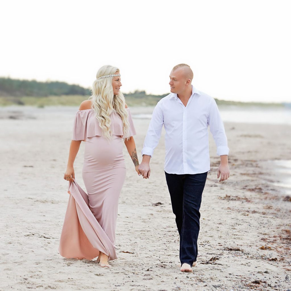 gravid kvinde og hendes mand paa en strand